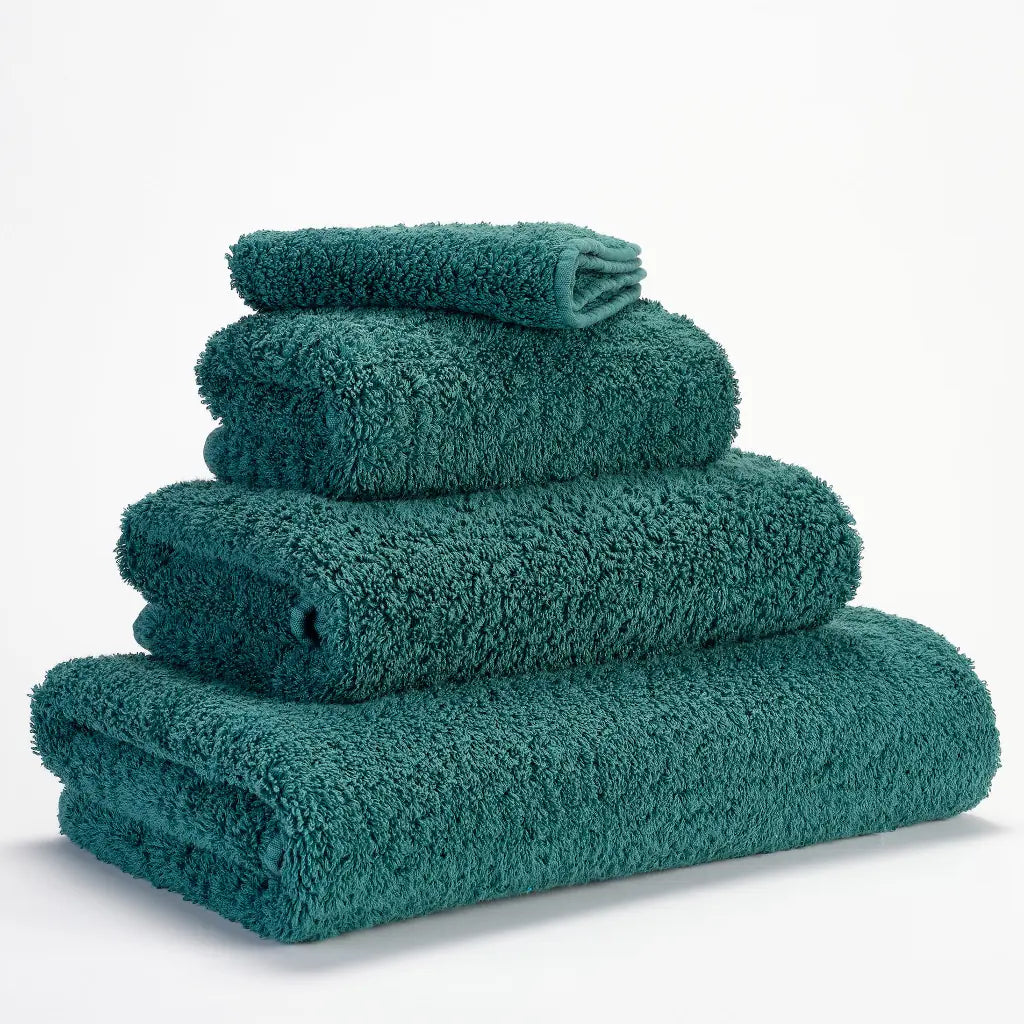 Set of teal towels stacked on a white background