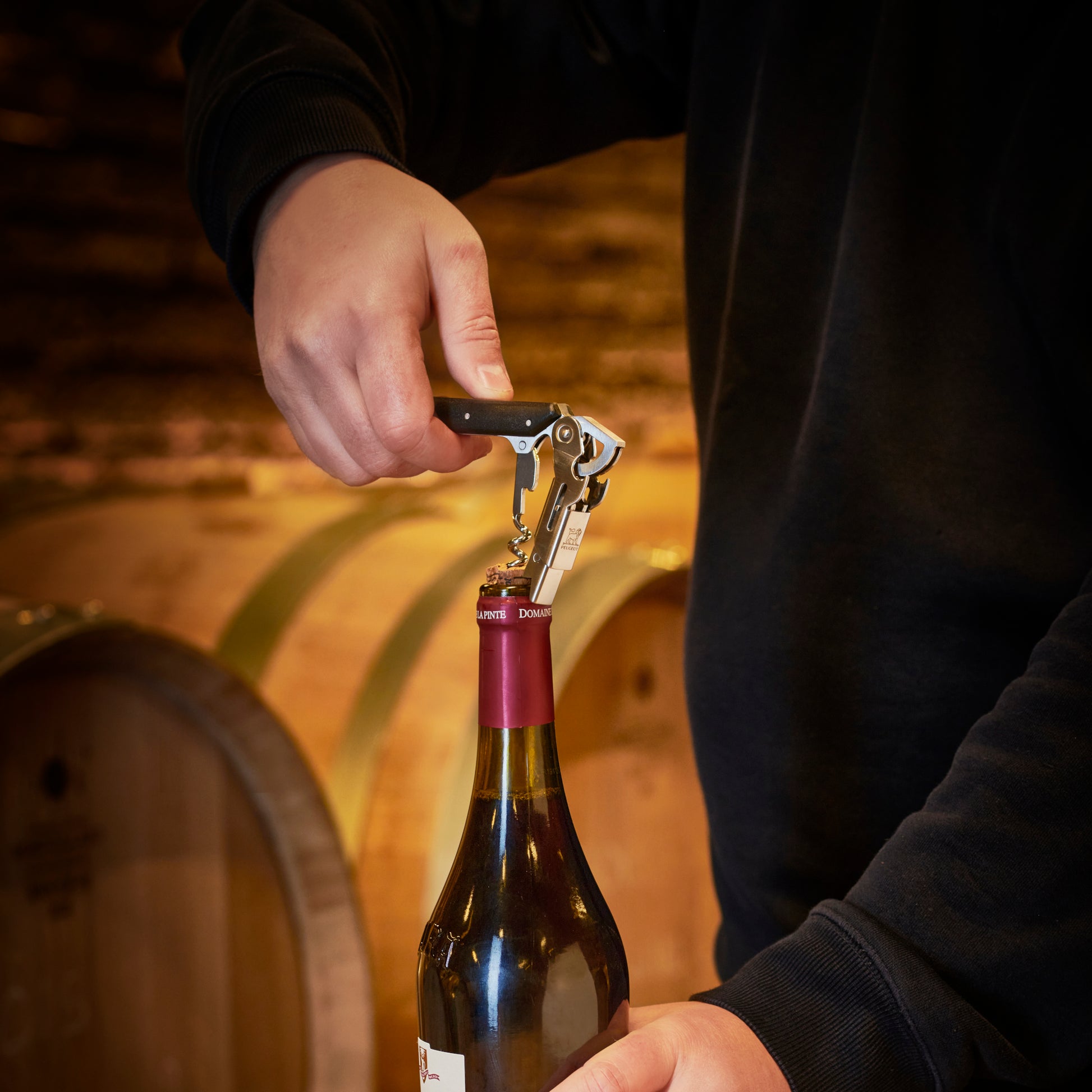 Person opening a wine bottle with Peugeot Clavelin Sommelier Waiter's Corkscrew