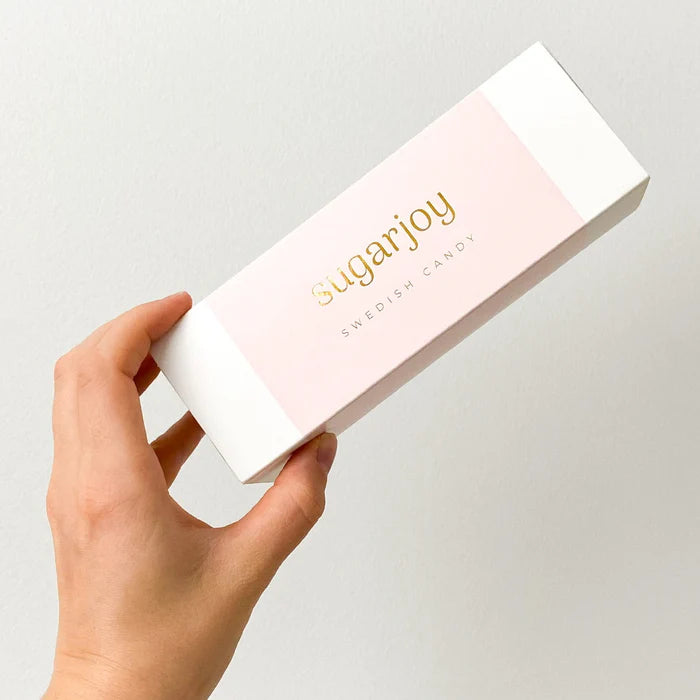 Hand holding a box of sugarjoy Pink Candy Box Duo against a light gray background