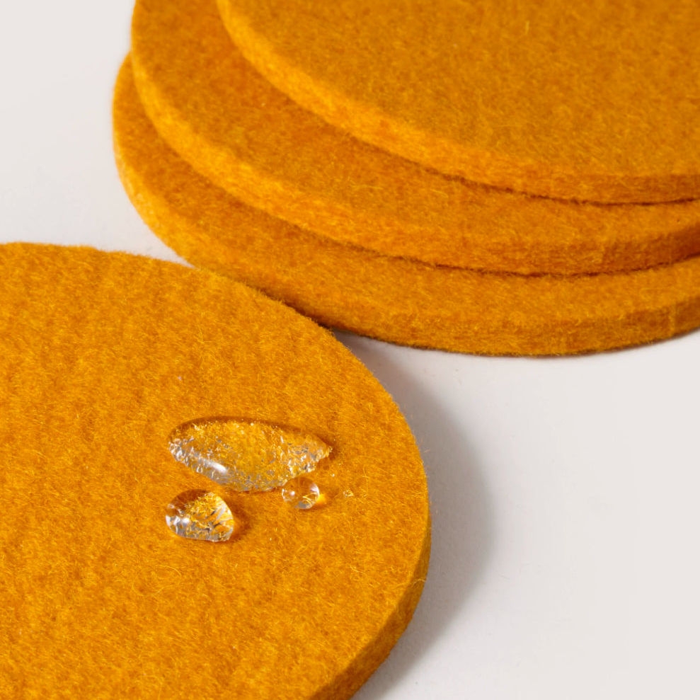 Orange felt coasters with water droplets on a white background