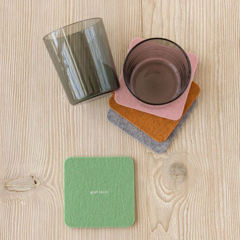 Colorful coasters on a wooden surface with two glasses.
