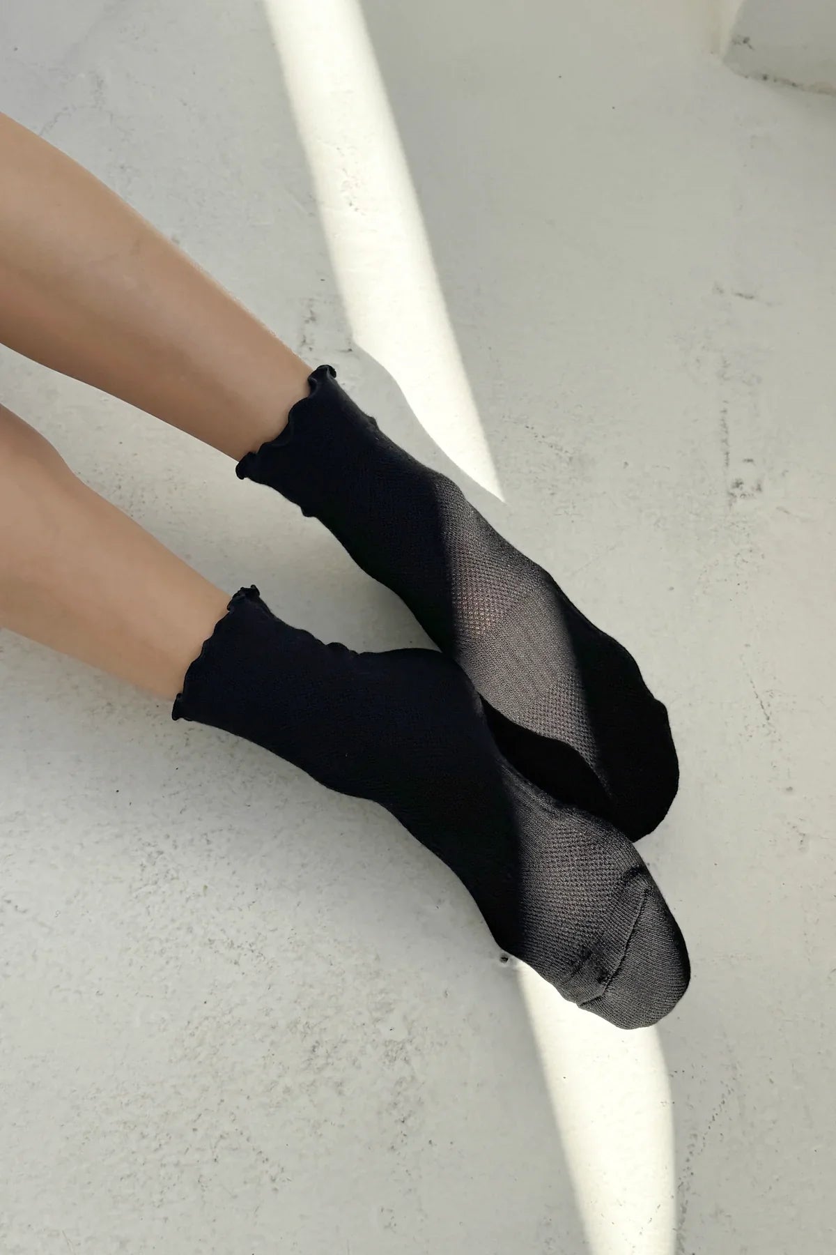 Black socks worn by a person on a light gray background