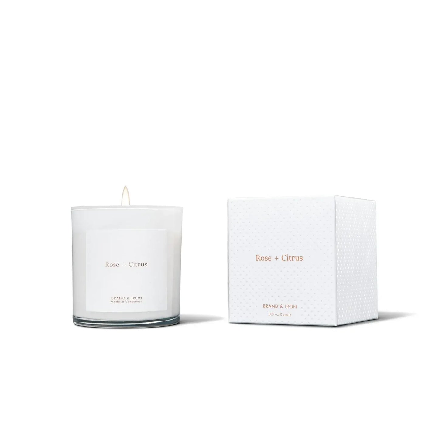 White candle with 'Rose + Citrus' branding next to its packaging on a white background