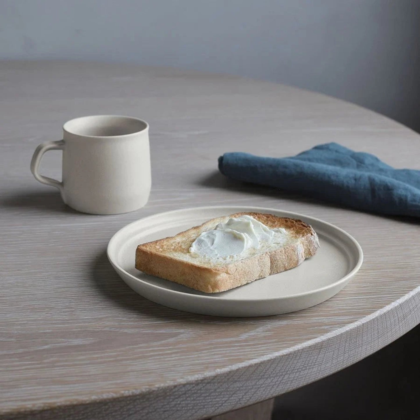 KINTO FOG mug in Ash White, 270ml next to plate with toast.