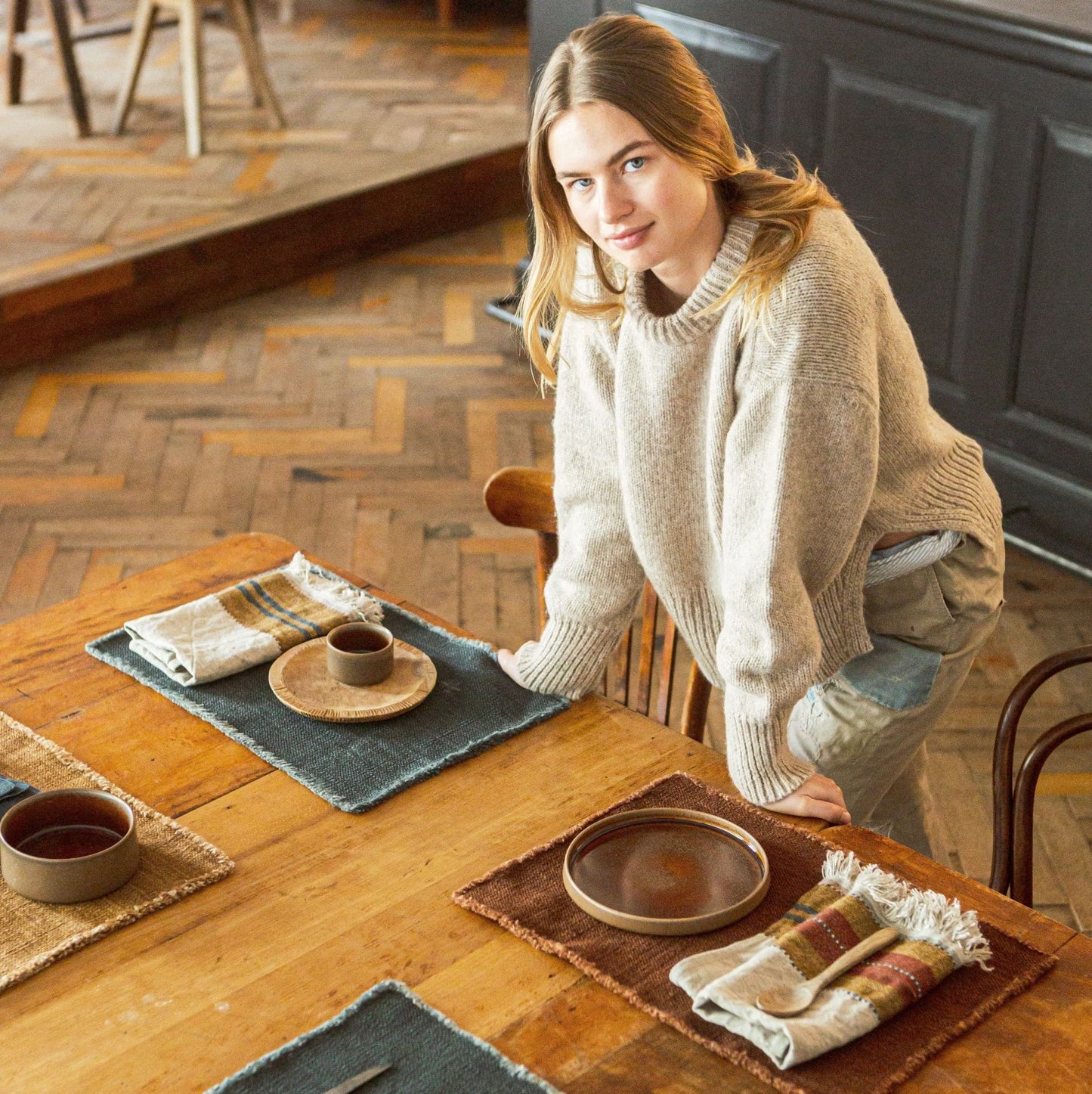 Woman in a sweater at a wooden table with Libeco Jasper Placemats