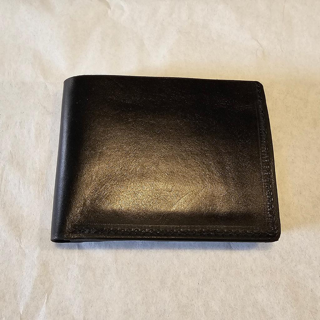Black leather wallet on a textured white surface