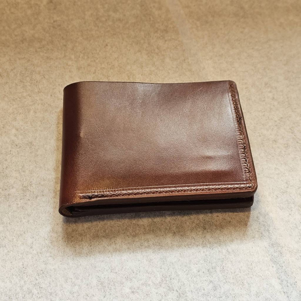 Brown leather wallet on a beige surface