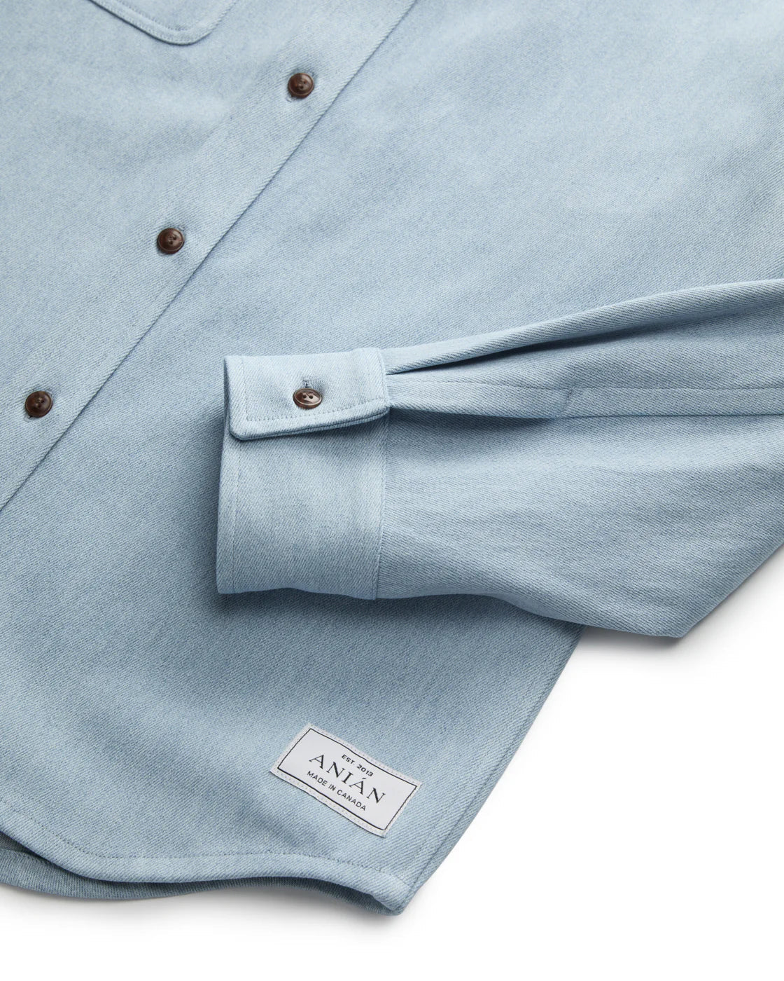 Light blue shirt with rolled-up sleeve and brand label on a white background