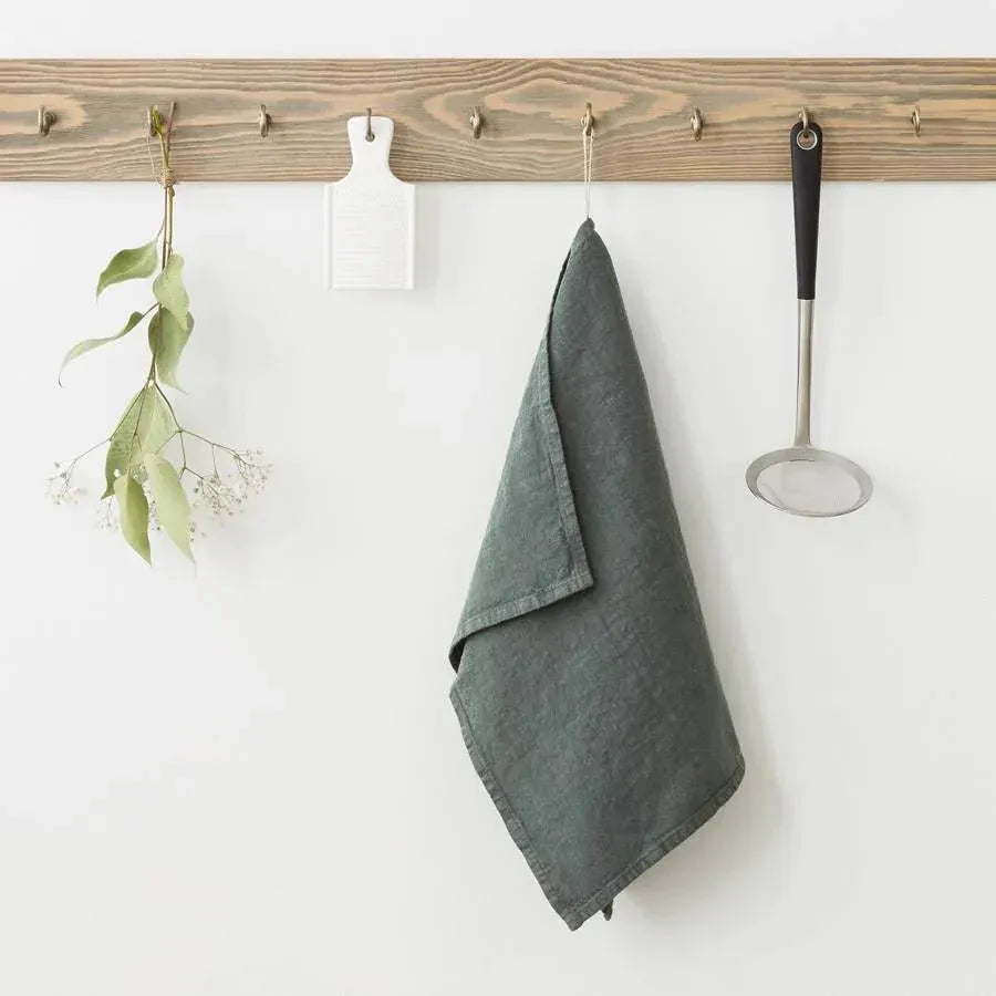 Forest green linen kitchen towel hanging on wooden rack