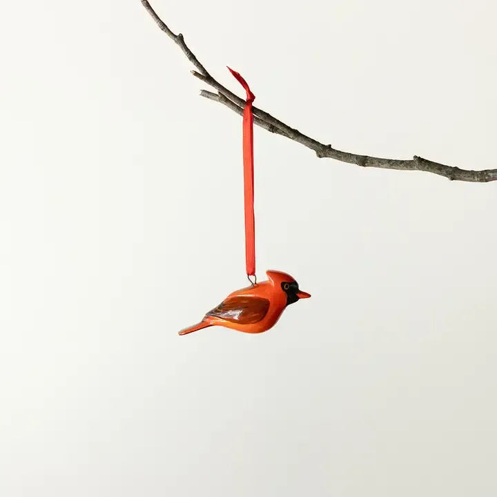 Cardinal bird ornament hanging from a branch against a white background