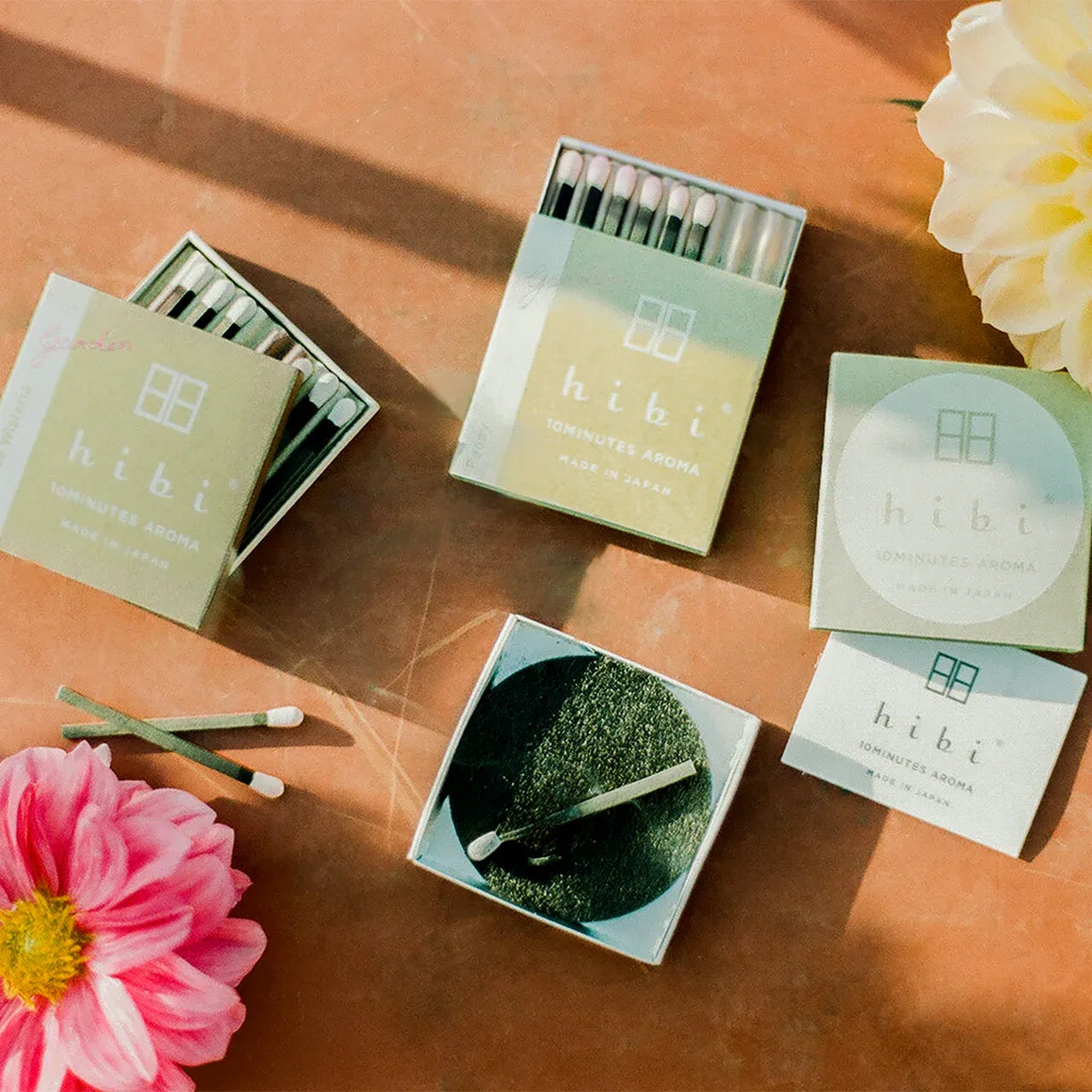 hibi products including matches and a small dish on a wooden surface with flowers.