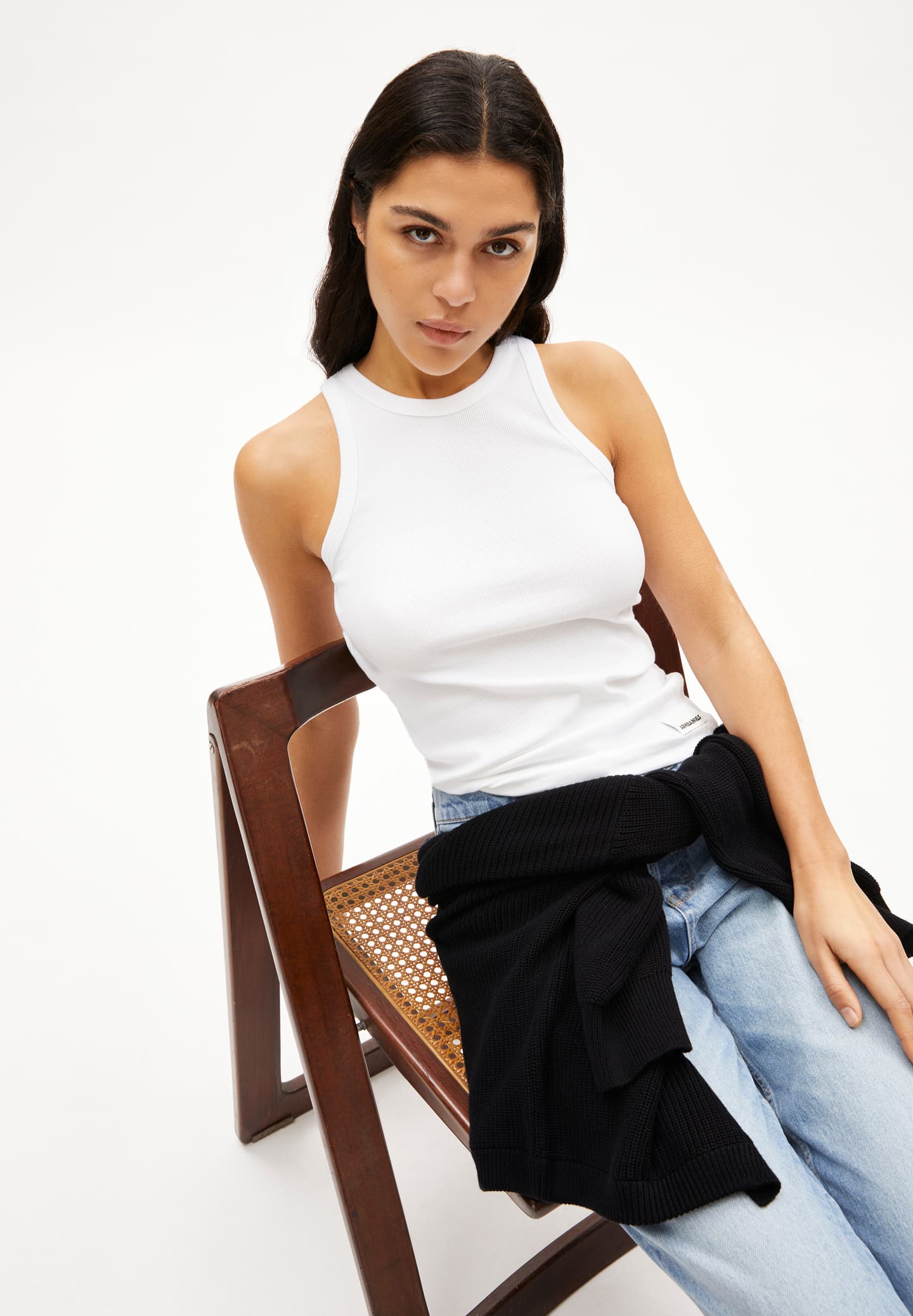 ARMEDANGELS Canada organic cotton white sleeveless ribbed tank top worn by model sitting on wooden chair