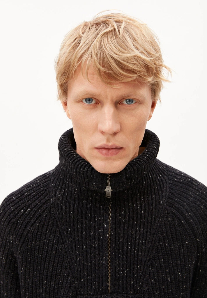 Close-up of the zipped-up stand collar and flecked rib knit on the ARMEDANGELS Canada Tweed Knit Half-Zip Sweater in black.