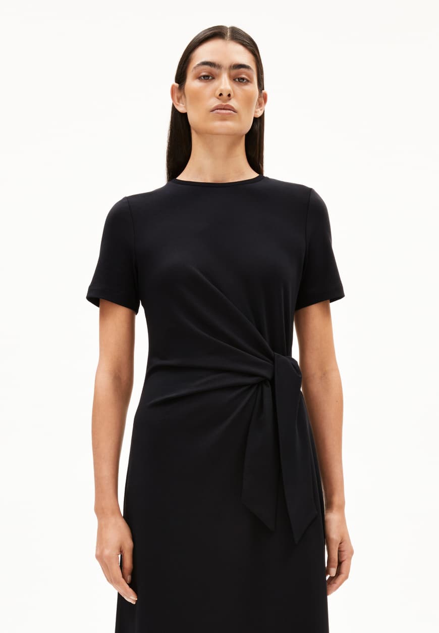 3/4 LENGTH PHOTO OF BLACK SHEATH WRAP DRESS ON MODEL WITH BLACK HAIR AGAINST WHITE BACKGROUND