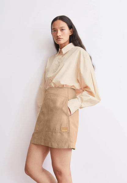 BARREL SLEEVE POPLIN BLOUSE in Pale Peach – ARMEDANGELS styled view on model with beige skirt