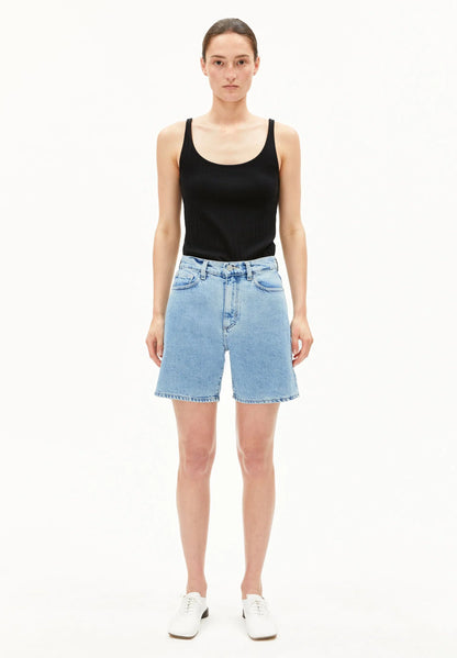 Woman wearing a black tank top and light blue denim shorts on a white background for Kelowna and Canada