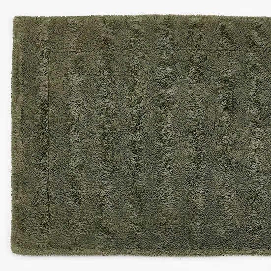 Green bath mat with textured surface on a white background