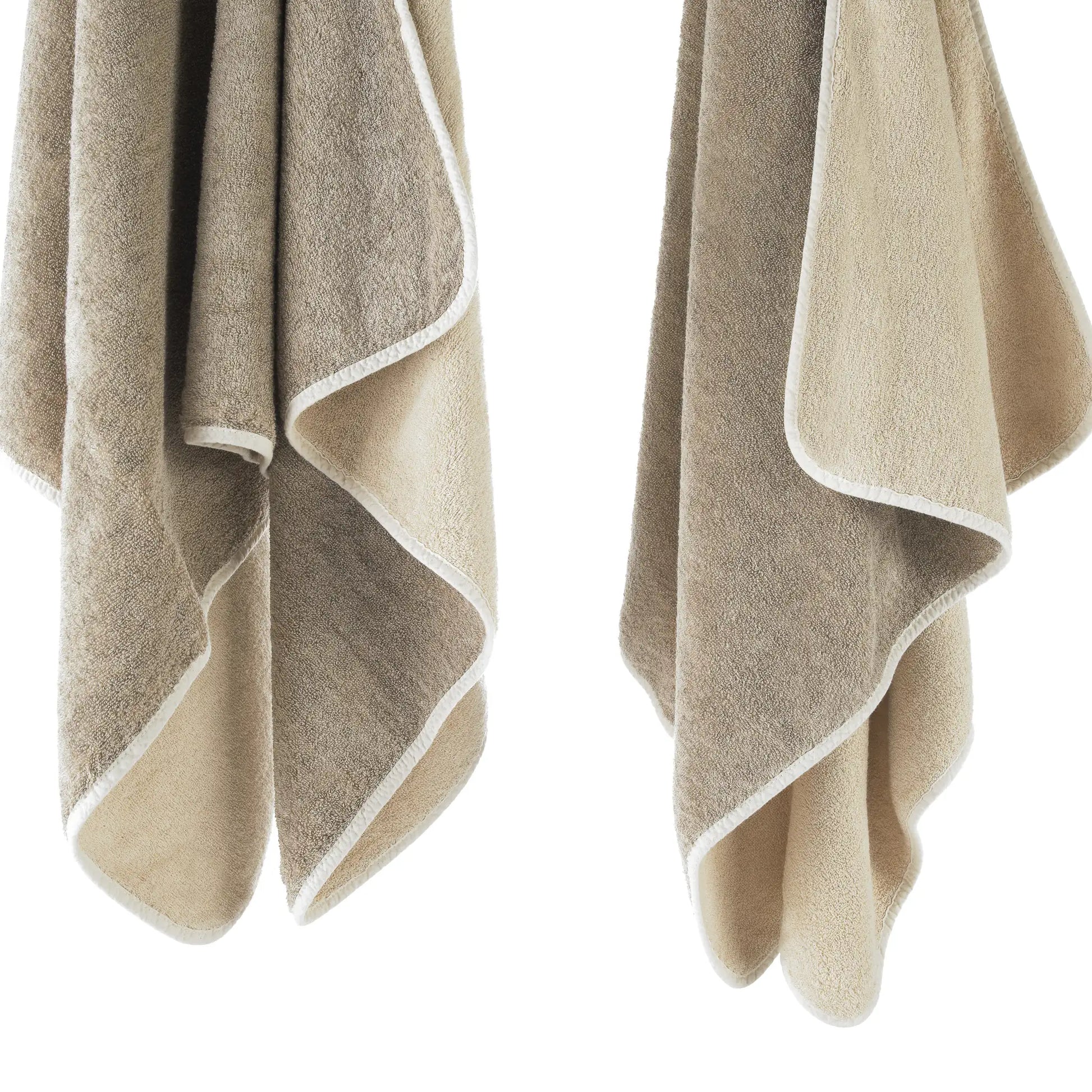 Two beige towels with white edges on a white background