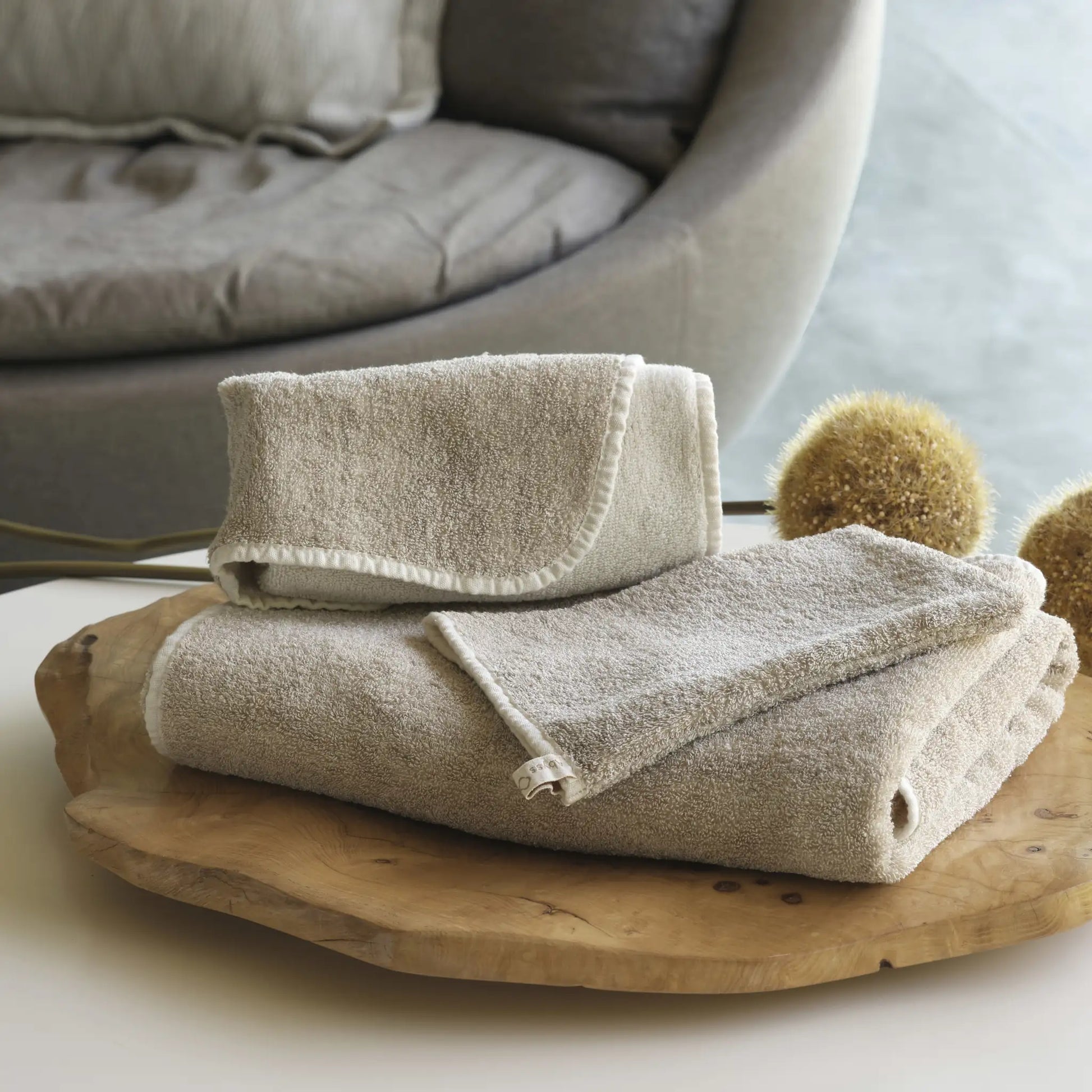 Folded beige towels on a wooden tray with a blurred background