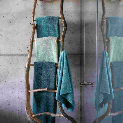 Abyss & Habidecor Super Pile Towels In blue/green, hanging on rustic log rack