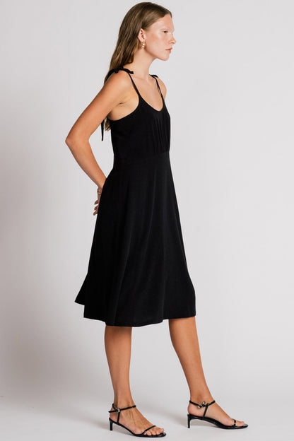 Allison Wonderland Manakin Dress in black, side view on model with white background, available at Textile Apparel Kelowna