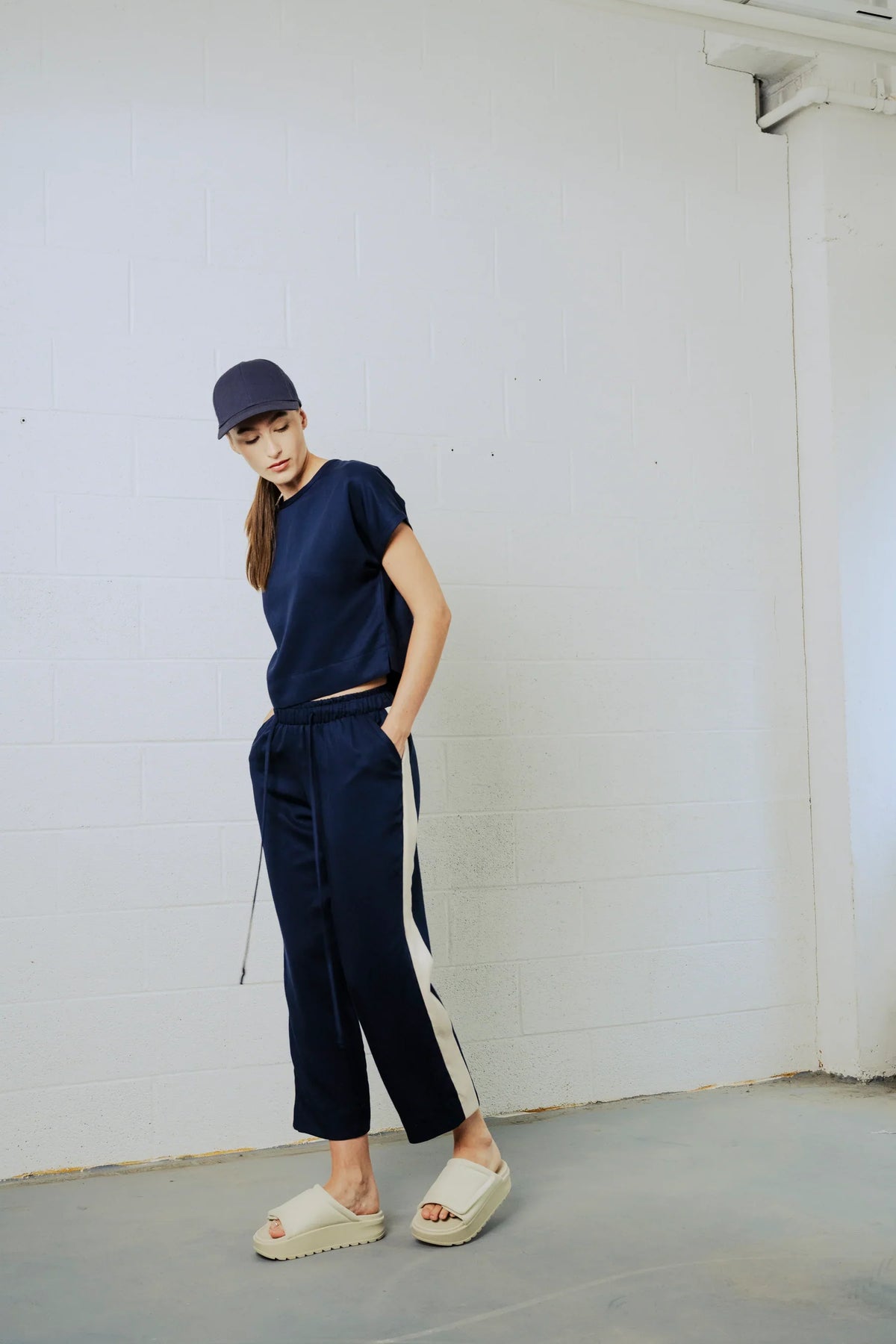 Person wearing a navy outfit with a white stripe against a plain background