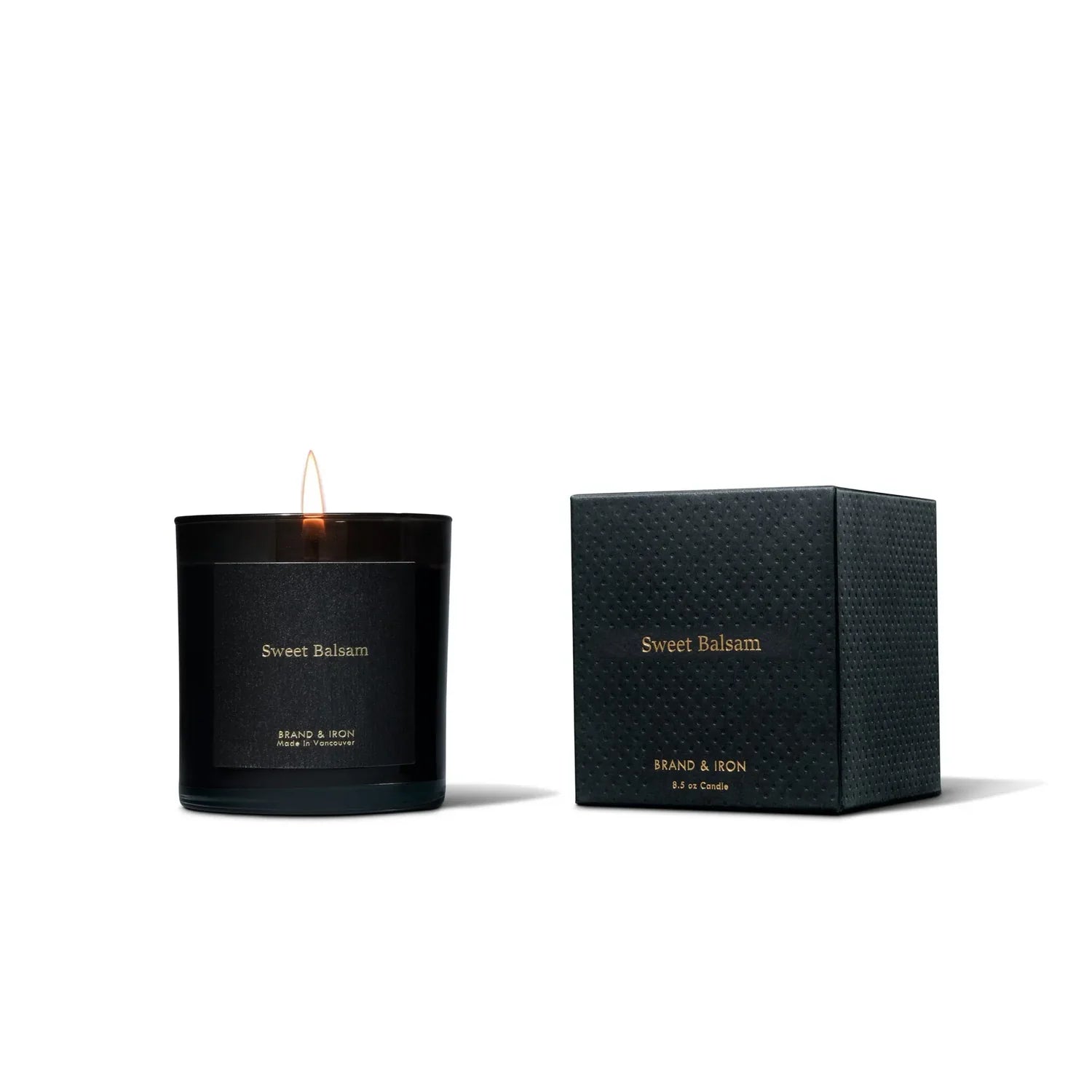 Black candle and packaging with 'Sweet Balsam' branding on a white background