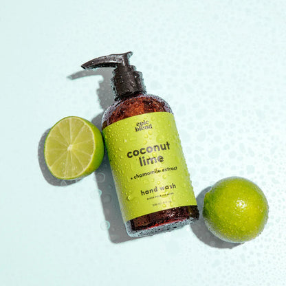 Coconut lime hand wash bottle with a pump next to a sliced lime on a light blue background