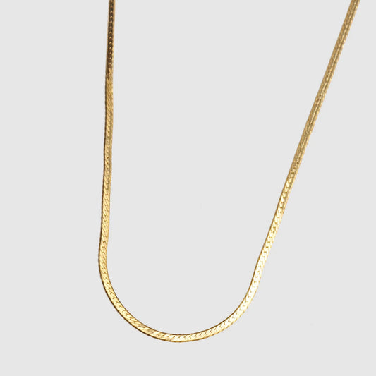 Gold chain necklace on a light gray background