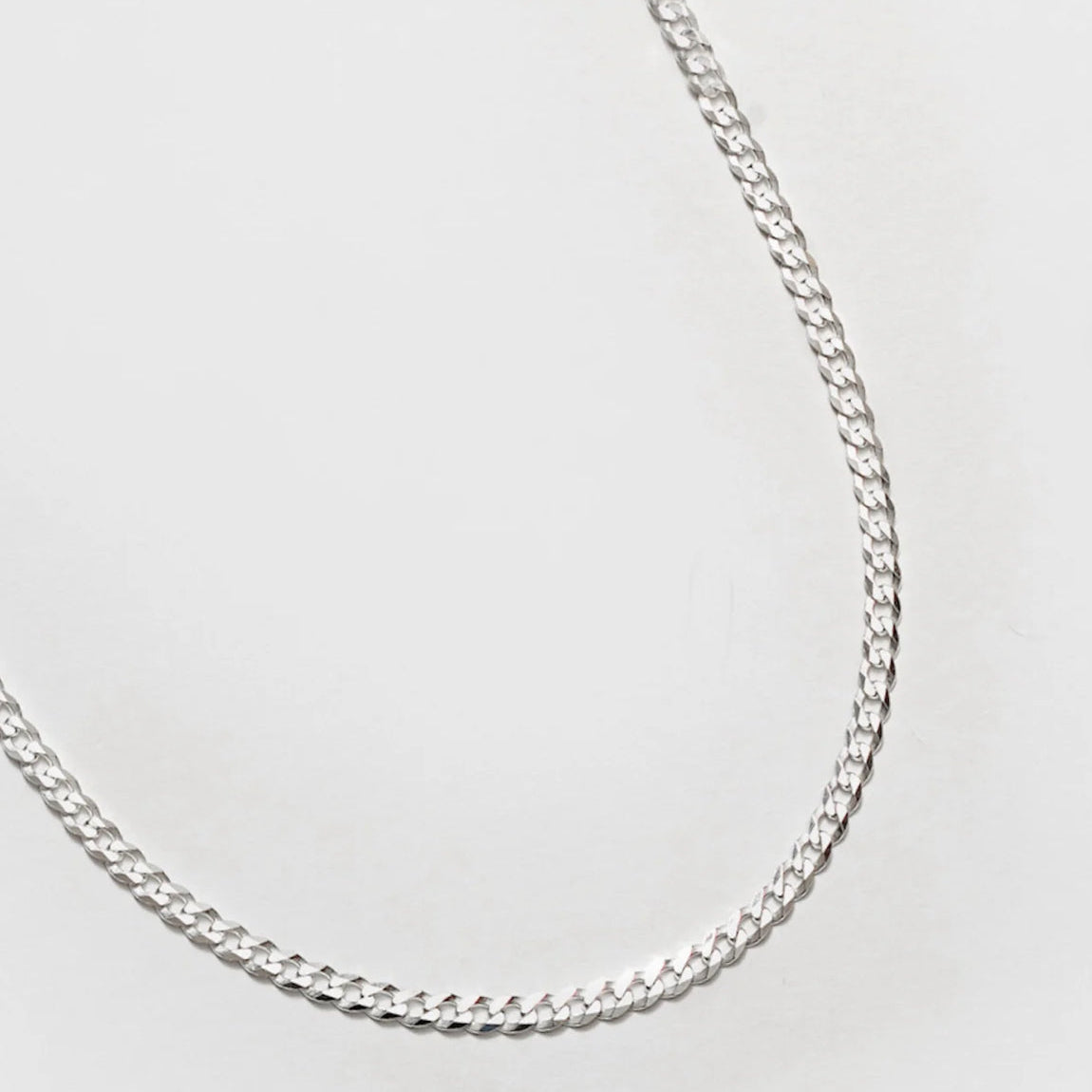 Silver chain necklace on a light gray background