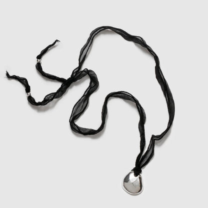A black silk necklace with a silver plated organic pendant and sterling silver end beads.