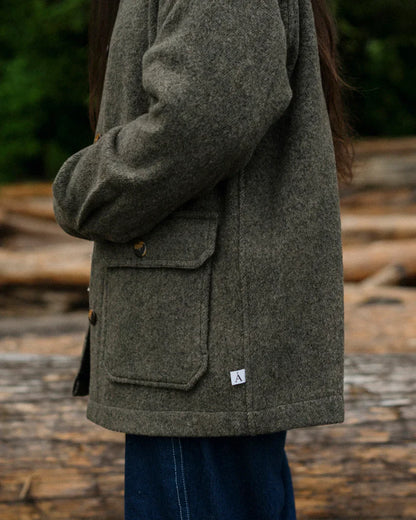women wearing green coat turned to the side standing outside 