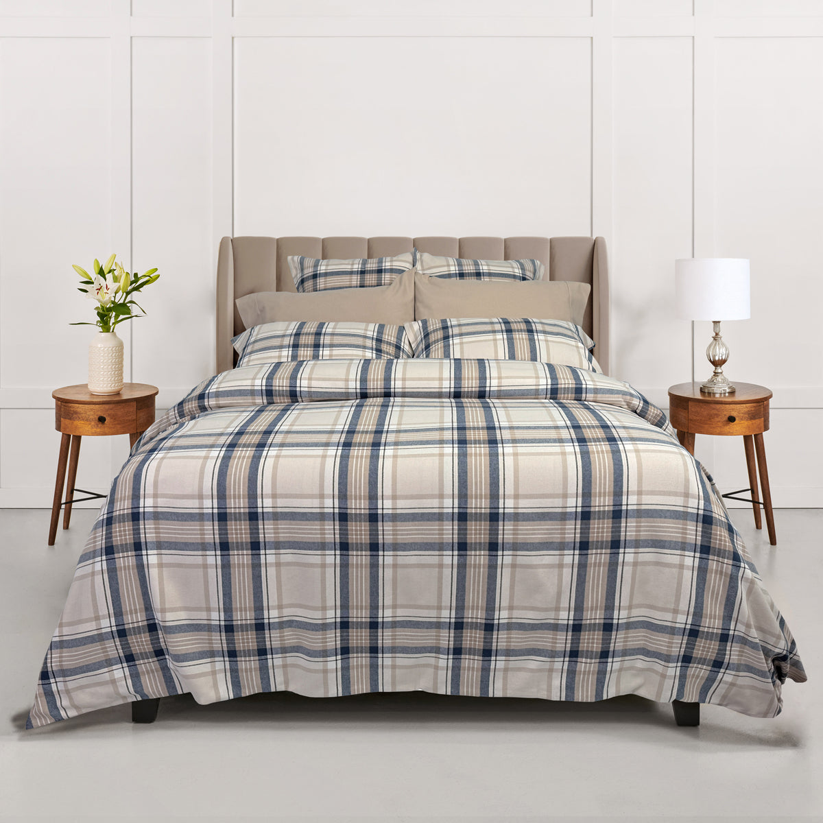 Plaid bedding set on a bed with matching pillows and side tables in a bedroom setting.