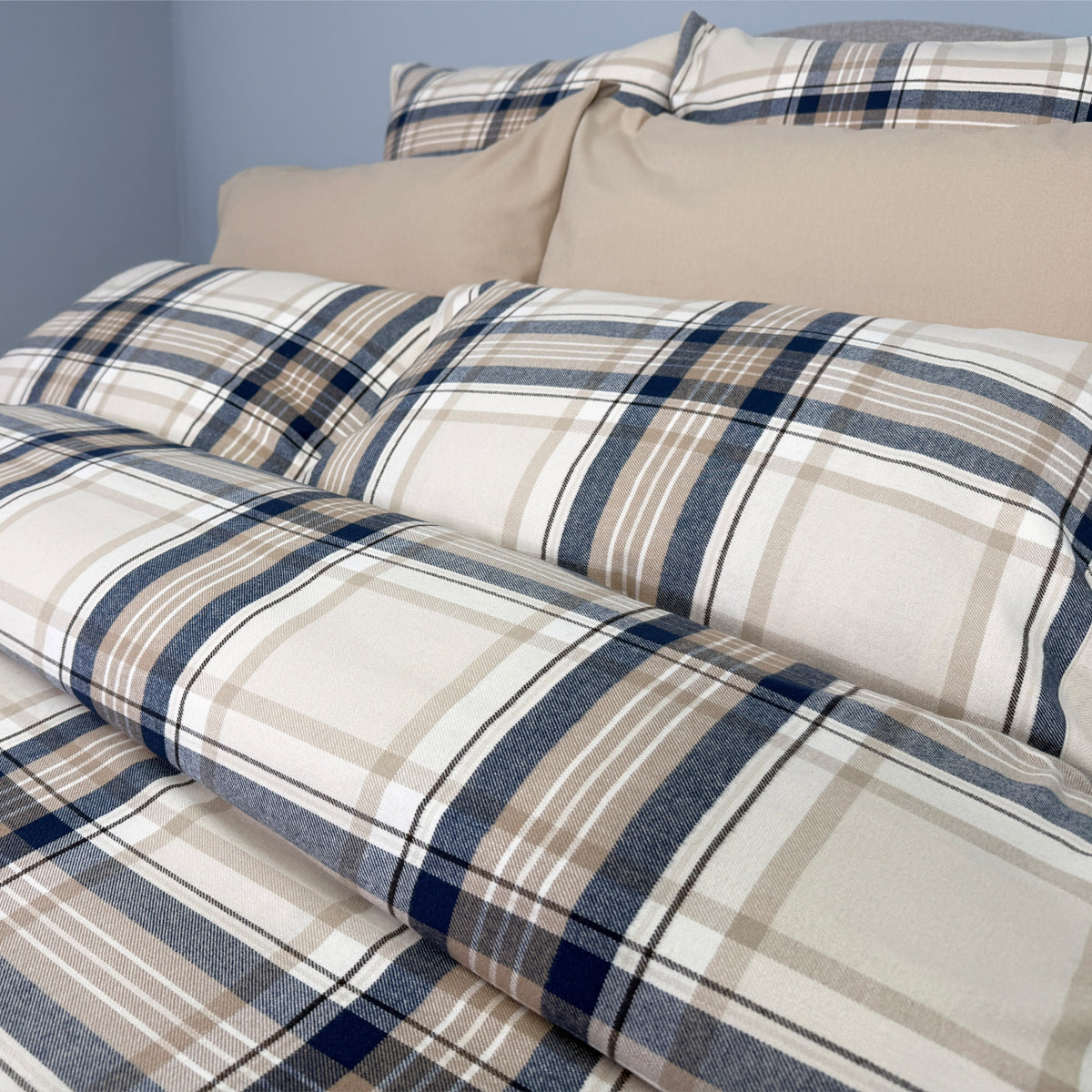 Plaid bedding set with beige and blue pattern on a bed.