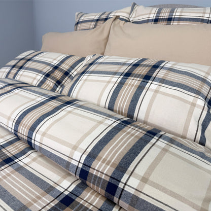Plaid bedding set with beige and blue pattern on a bed.