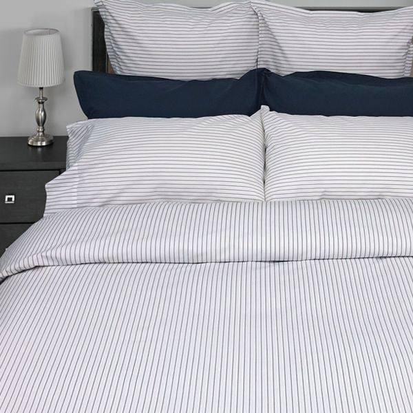 Striped bedding set on a bed with a nightstand and lamp in the background.