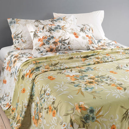 Floral bedding set with green and orange flowers on a bed against a gray wall.