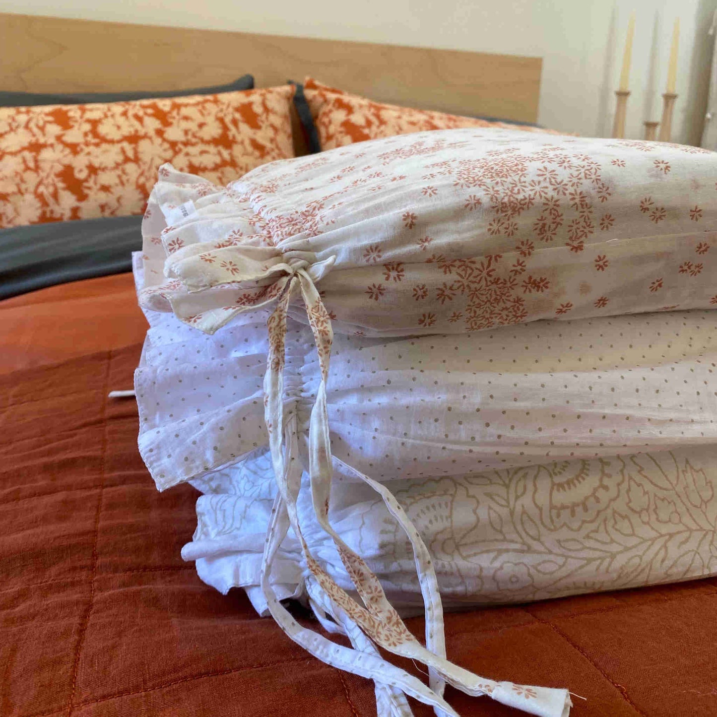 A folded cotton duvet cover with floral hand block print, displayed on a bed.