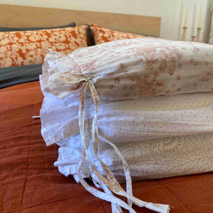 A folded cotton duvet cover with floral hand block print, displayed on a bed.