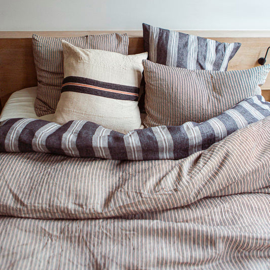 A queen-sized duvet cover with a striped pattern in black and old rose colors displayed on a bed with matching pillows.