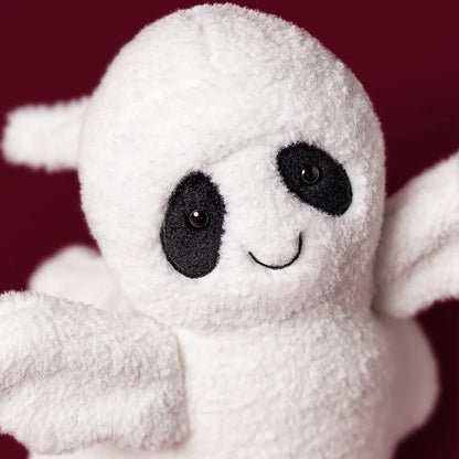 A close-up of a white plush ghost toy with black embroidered eyes, a curved smile, and small wings, set against a dark burgundy background.