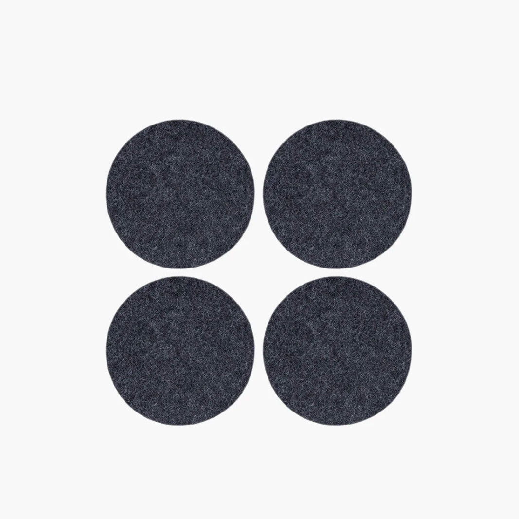 Four dark gray circular coasters on a white background