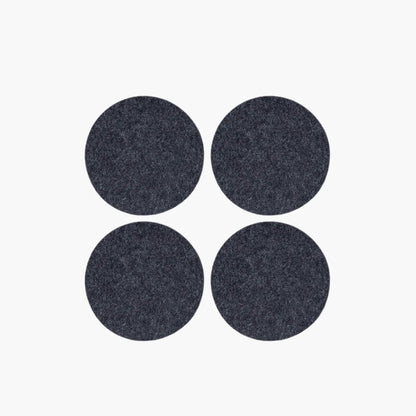 Four dark gray circular coasters on a white background