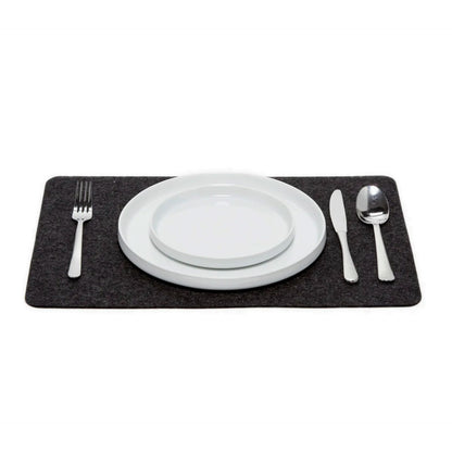 A charcoal-coloured Merino wool rectangle placemat on a white plate with silverware on top, placed on a white background.