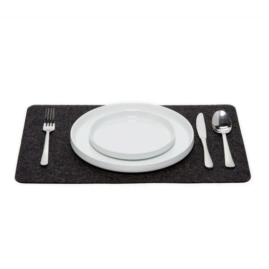 A charcoal-coloured Merino wool rectangle placemat on a white plate with silverware on top, placed on a white background.