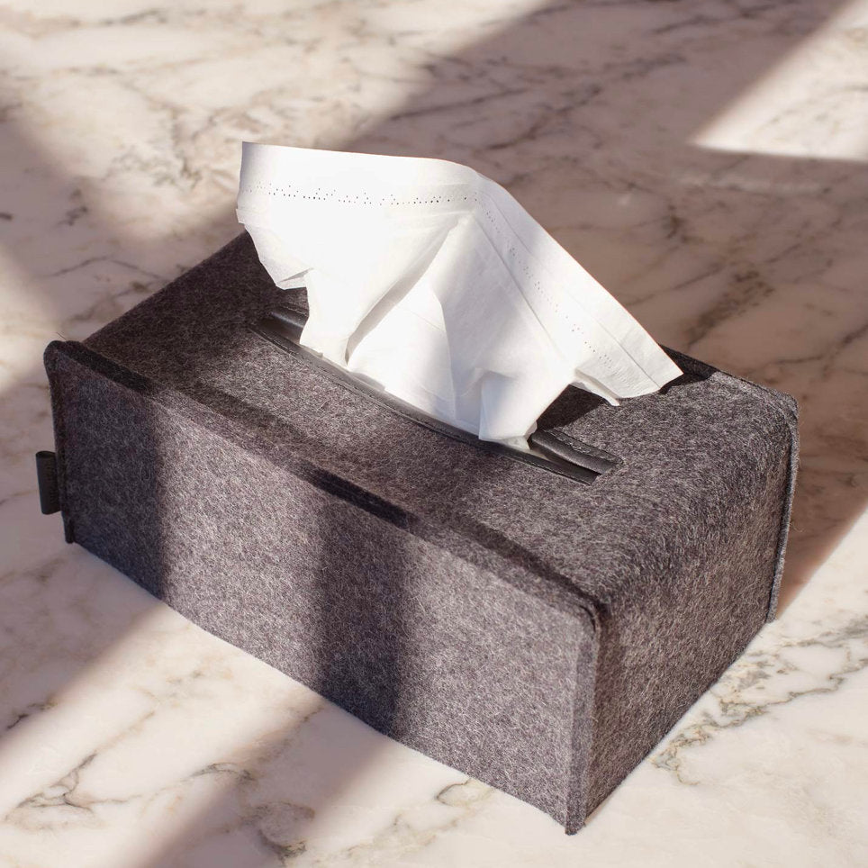 Gray tissue box with tissues on a marble surface