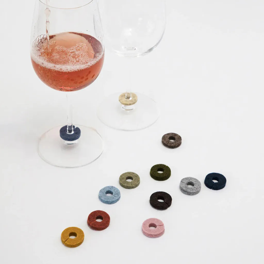 Wine glass with colorful drink markers on a white surface