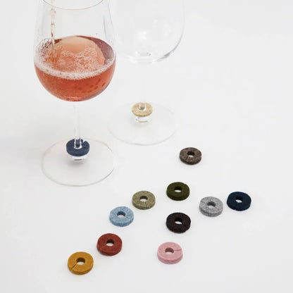 Wine glass with colorful drink markers on a white surface