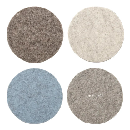 Four round coasters in gray, blue, and beige on a light gray background.