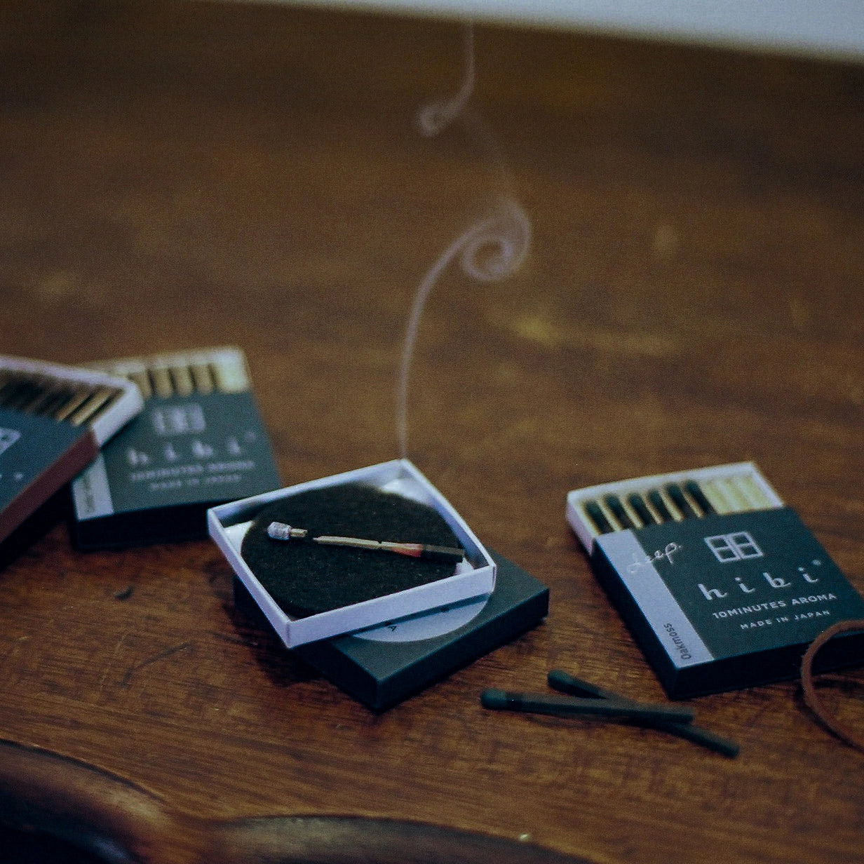 hibi Oak Moss Incense Match lit on wooden table